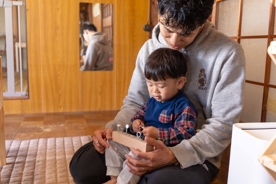 大人の膝で一緒に教具に取り組む子ども